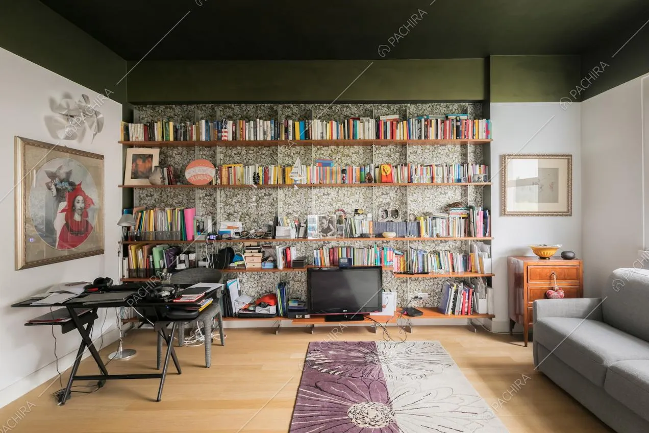 Salotto con carta da parati, libreria, parquet e soffitto verde