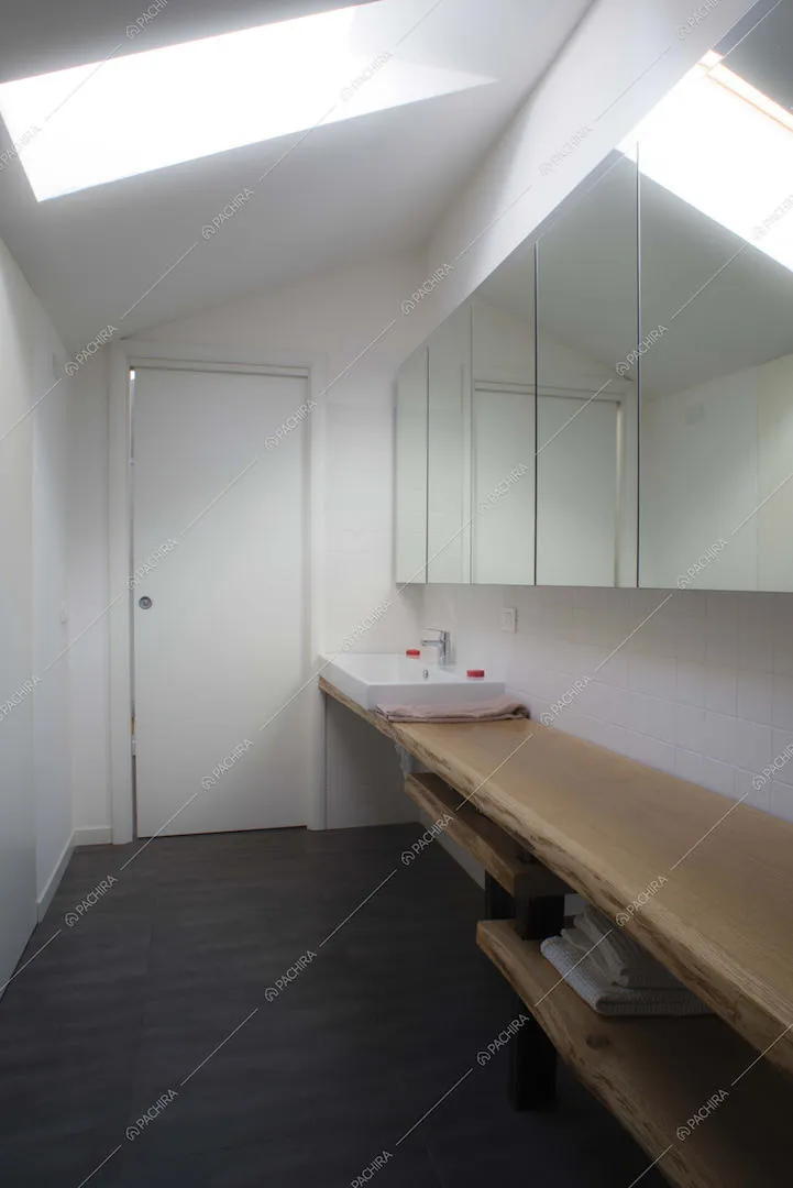 Bagno con pavimento in parquet e specchi per tutta la parete