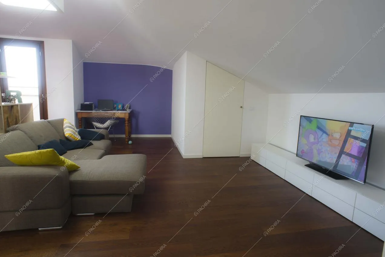 Divano angolare, parete lilla scuro e televisore
