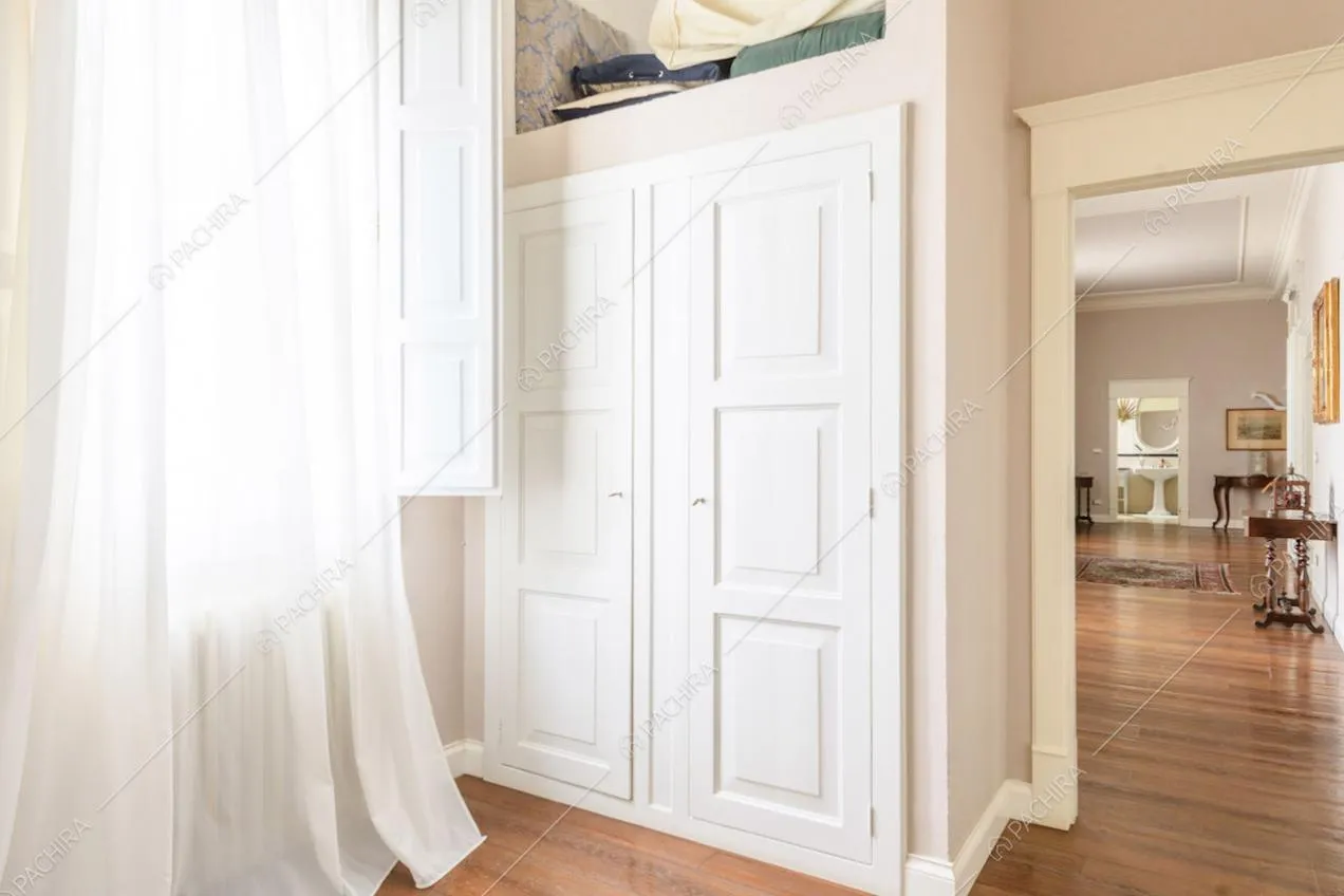 Armadio bianco a muro con boiserie sulle ante bianche e pavimento in parquet