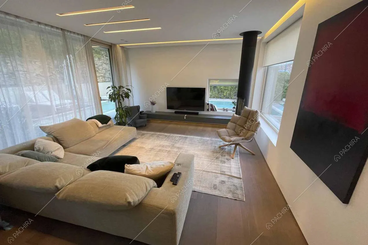Divano angolare del salotto con pavimento in parquet, vista sulla piscina dalle vetrate