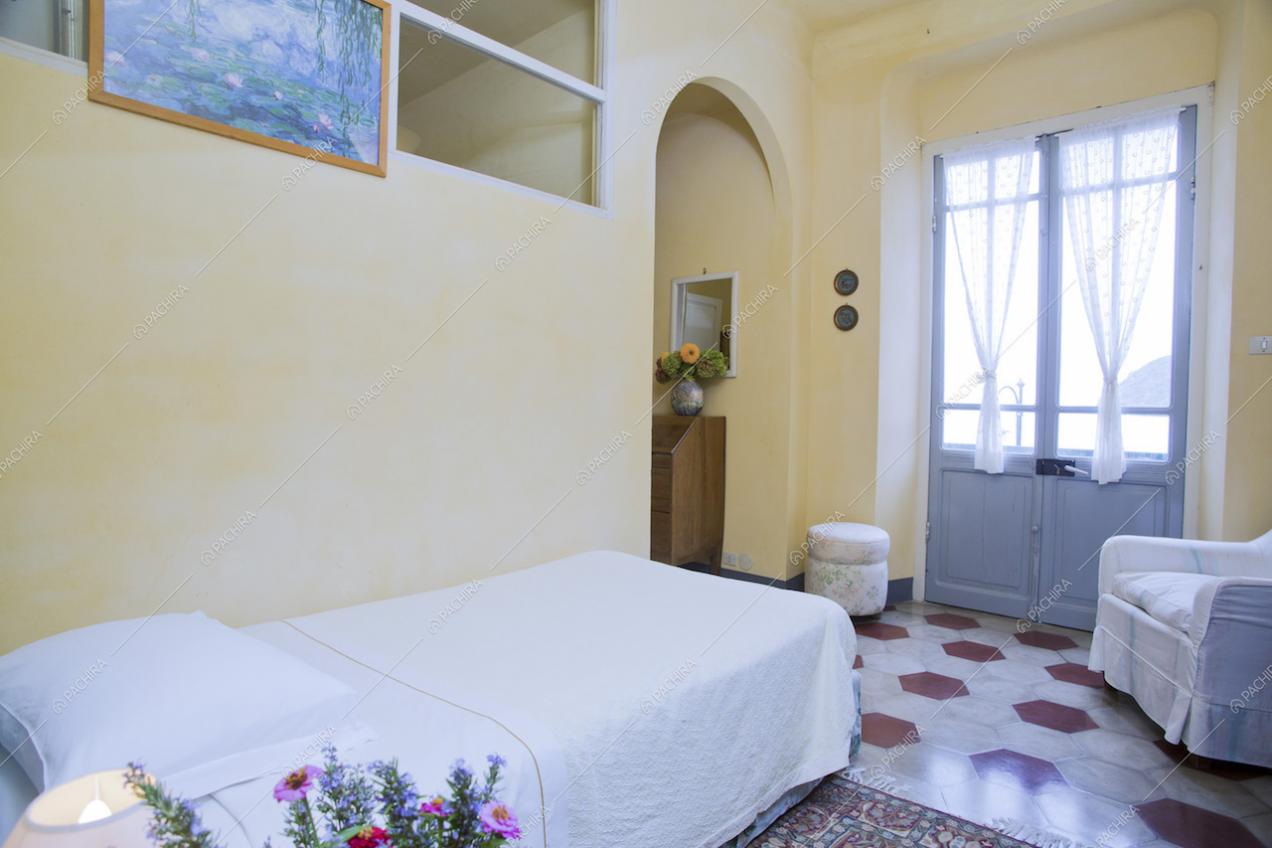 Letto singolo in camera con poltrona e porta finestra