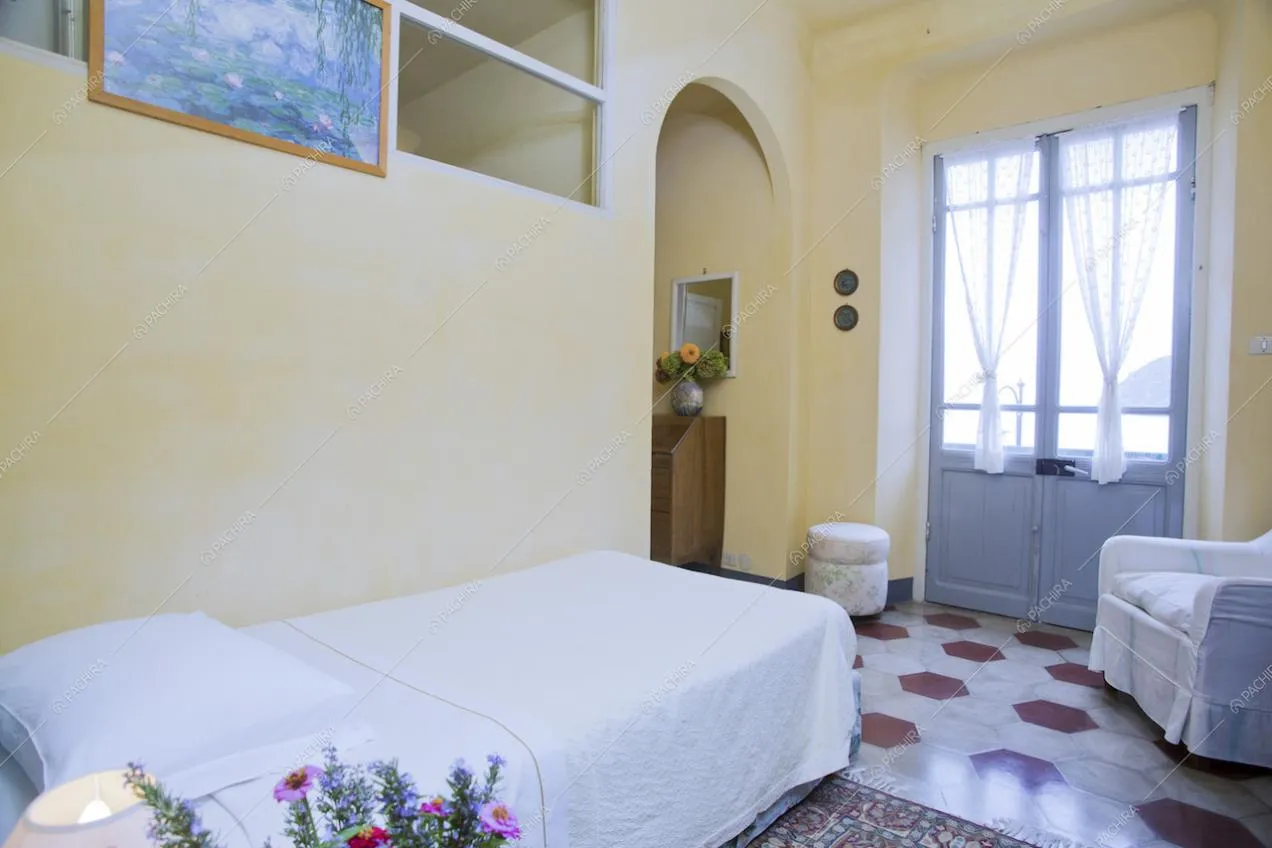 Letto singolo in camera con poltrona e porta finestra