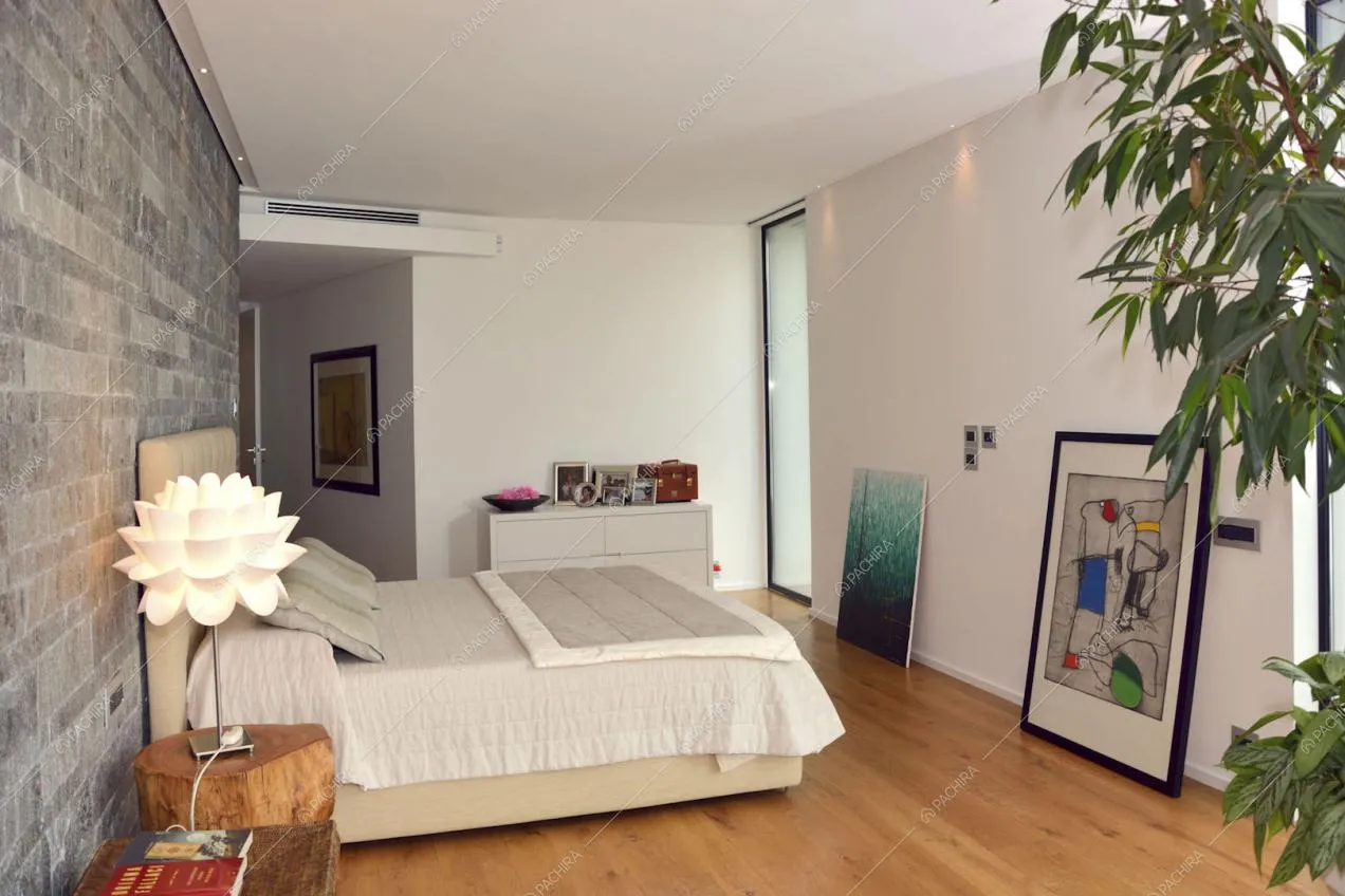 Camera da letto con parete in pietra e pavimento in parquet