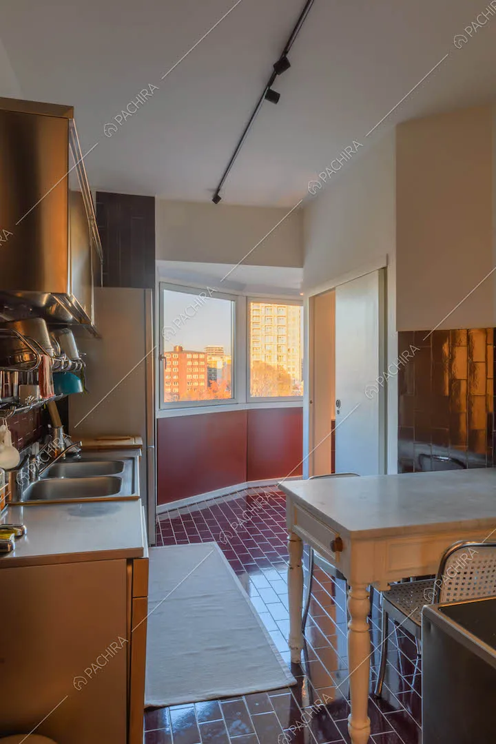 Tavolo da pranzo nella cucina a pareti con fornelli a induzione e vista sullo skyline