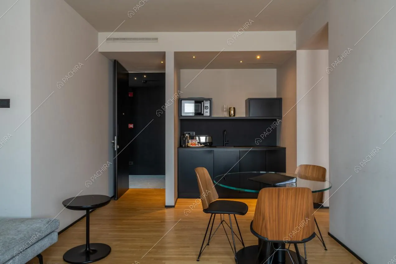 Cucina a parete a vista nera con fornelli a induzione e tavolo da pranzo con sedie di legno