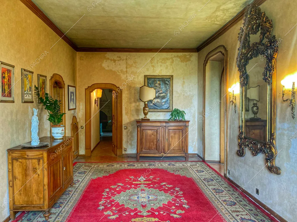 Atrio con specchio dalla cornice antica, grande tappeto e carta da parati beige