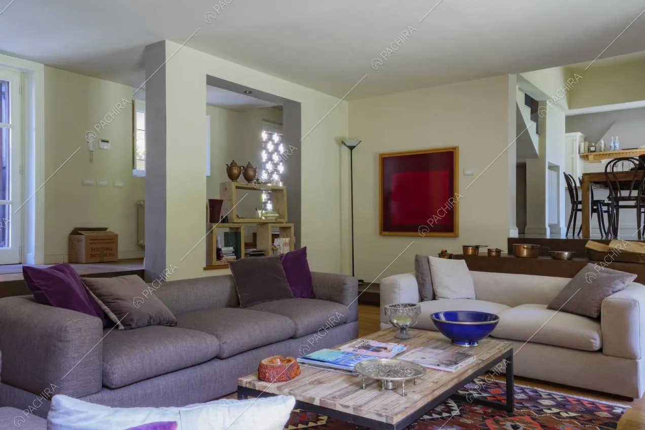 Divani viola nel salotto con pavimento in parquet e vista su tavolo da pranzo e cucina
