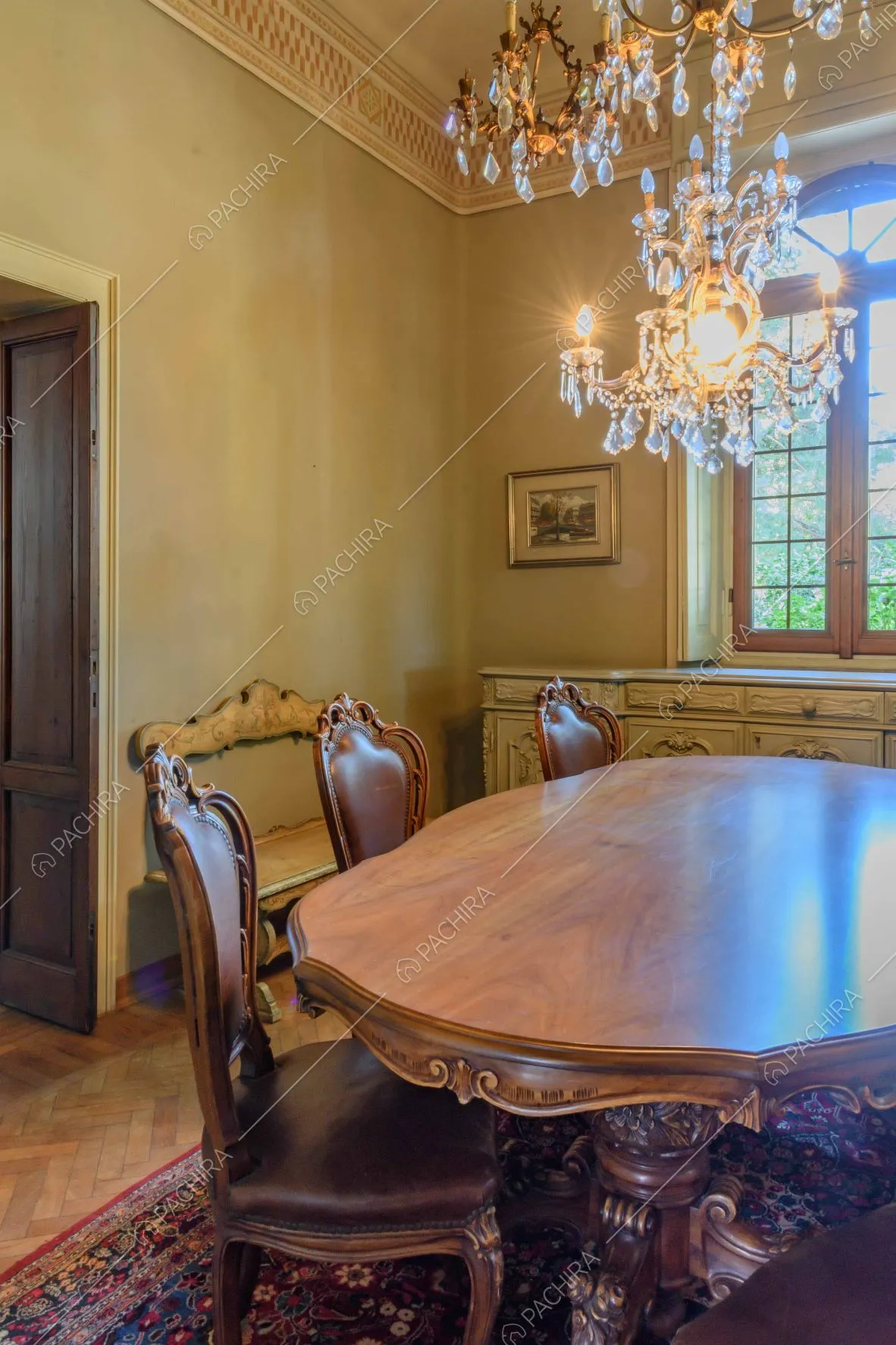 Tavolo da pranzo in legno lavorato nella sala con lampadario in cristallo