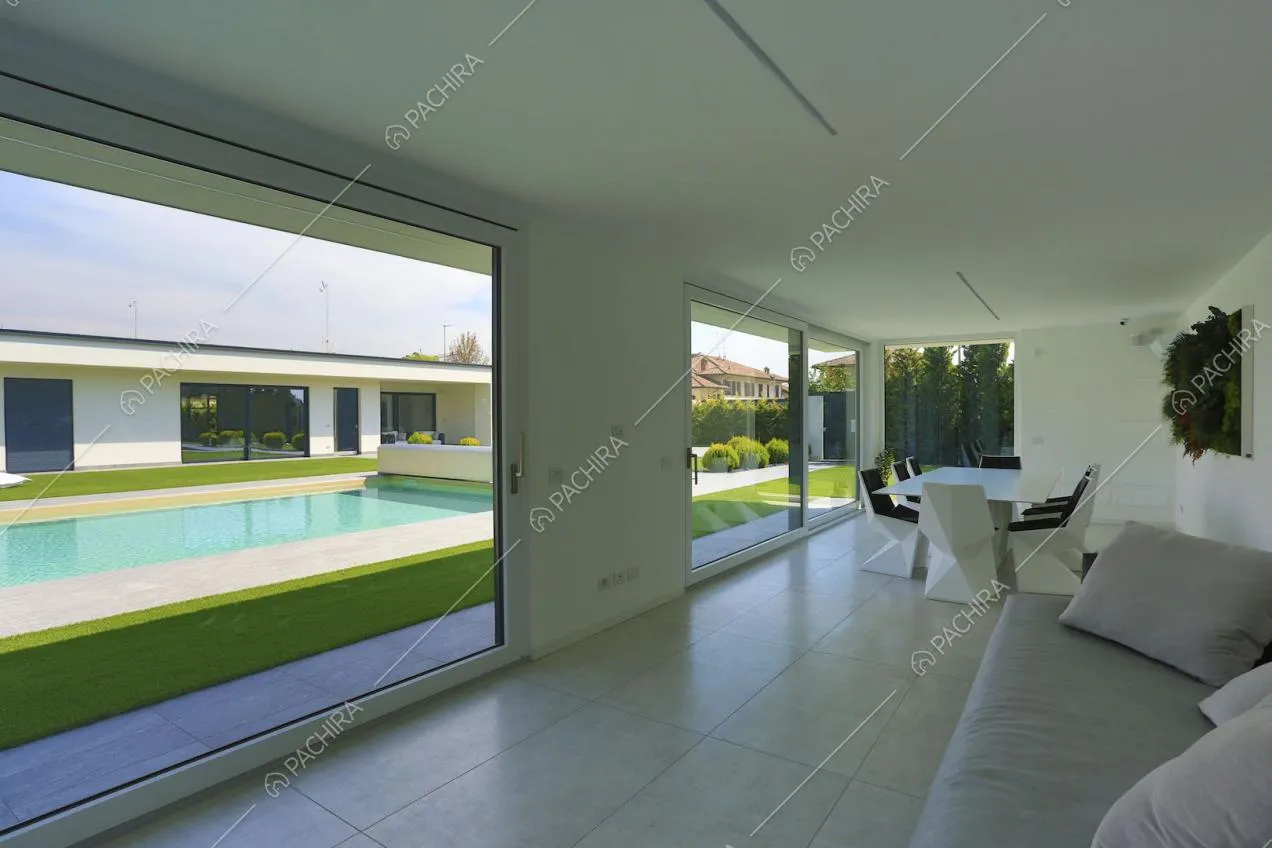 Dal divano vista sulla piscina attraverso le ampie vetrate scorrevoli