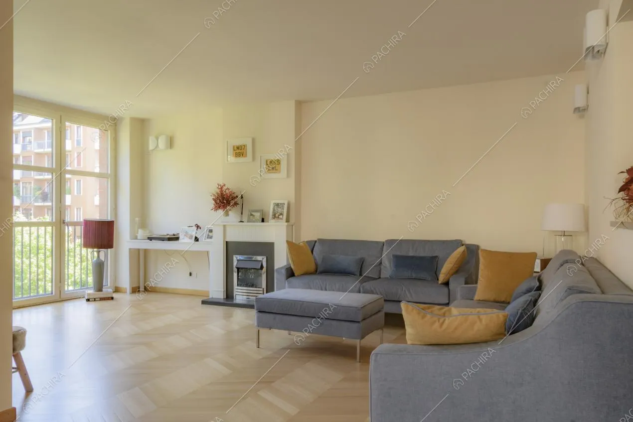 Luminoso soggiorno con pavimento in parquet, divano e camino