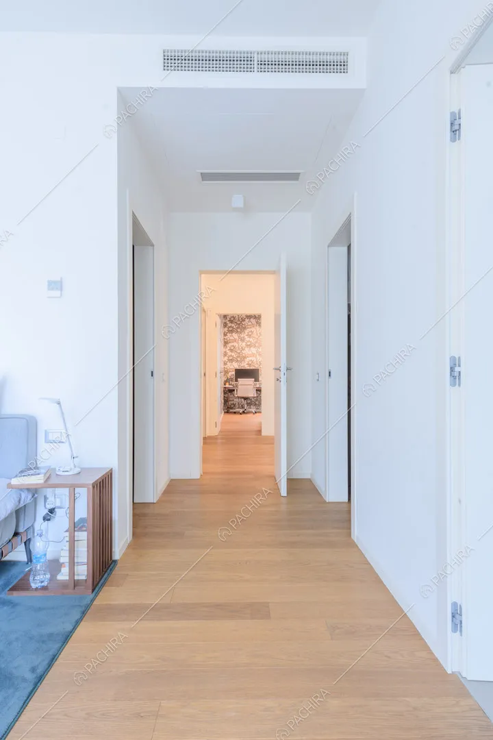 Pavimento in parquet nel grande corridoio con pareti bianche e vista sullo studio