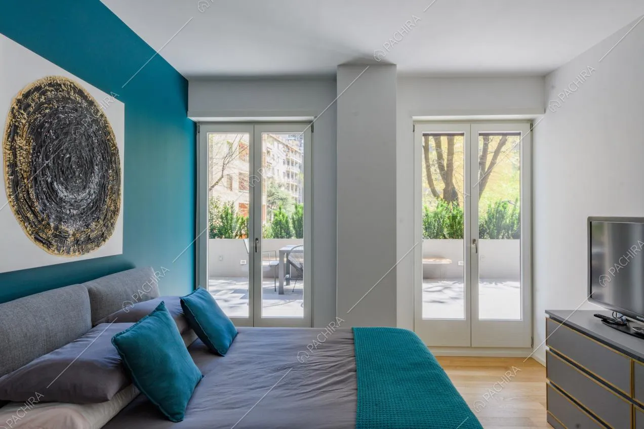 Luminosa camera da letto matrimoniale con parete blu e vista sulla terrazza