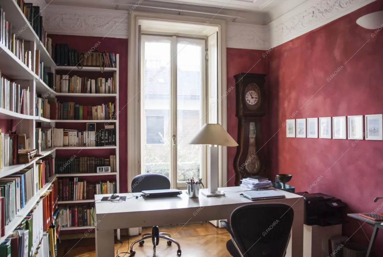 Studio con pareti rosse e boiserie e scrivania bianca