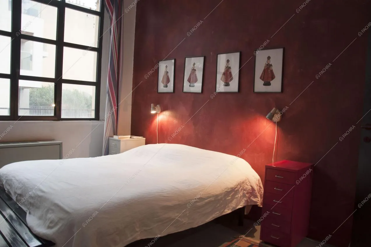 Camera da letto con parete rossa e comodino in metallo rosso