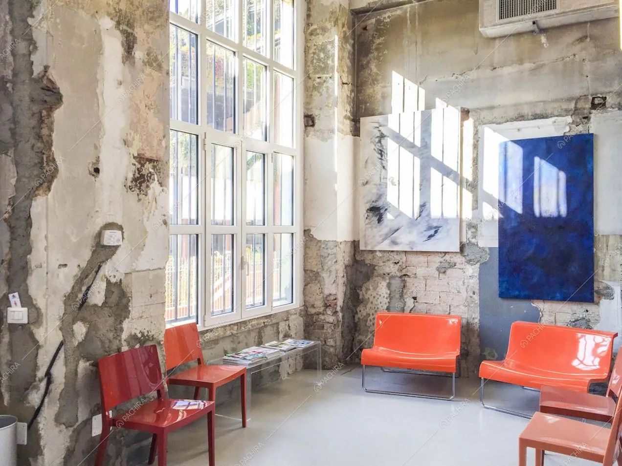 Sala d'attesa con sedie colorate e pareti delabré