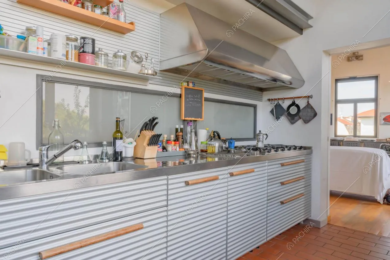 Cucina a parete con lavandino, fornelli a gas e vista sui divani del salotto