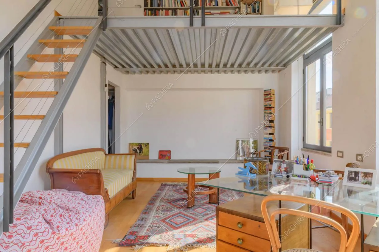 Studio con pavimento in parquet e soppalco in metallo con letto