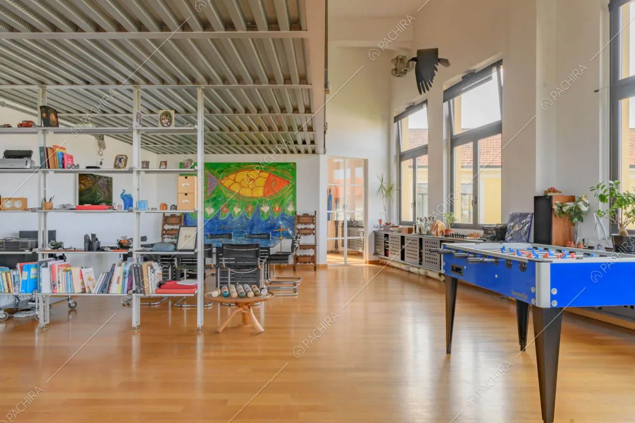 Pavimento in parquet nella sala con soppalco in metallo, grandi vetrate e pareti bianche