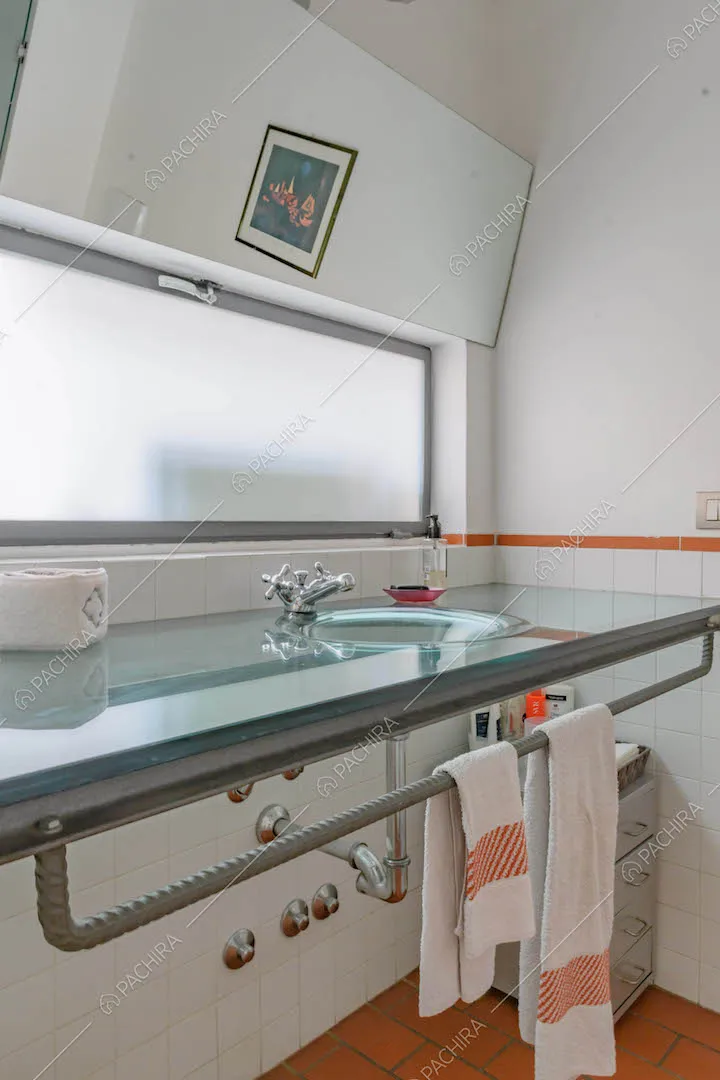Bagno con lavandino sul mobile bagno sospeso in cristallo e pareti bianche