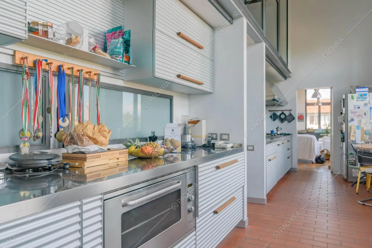 Cucina a parete con pavimento in cotto e vista sui divani del salotto