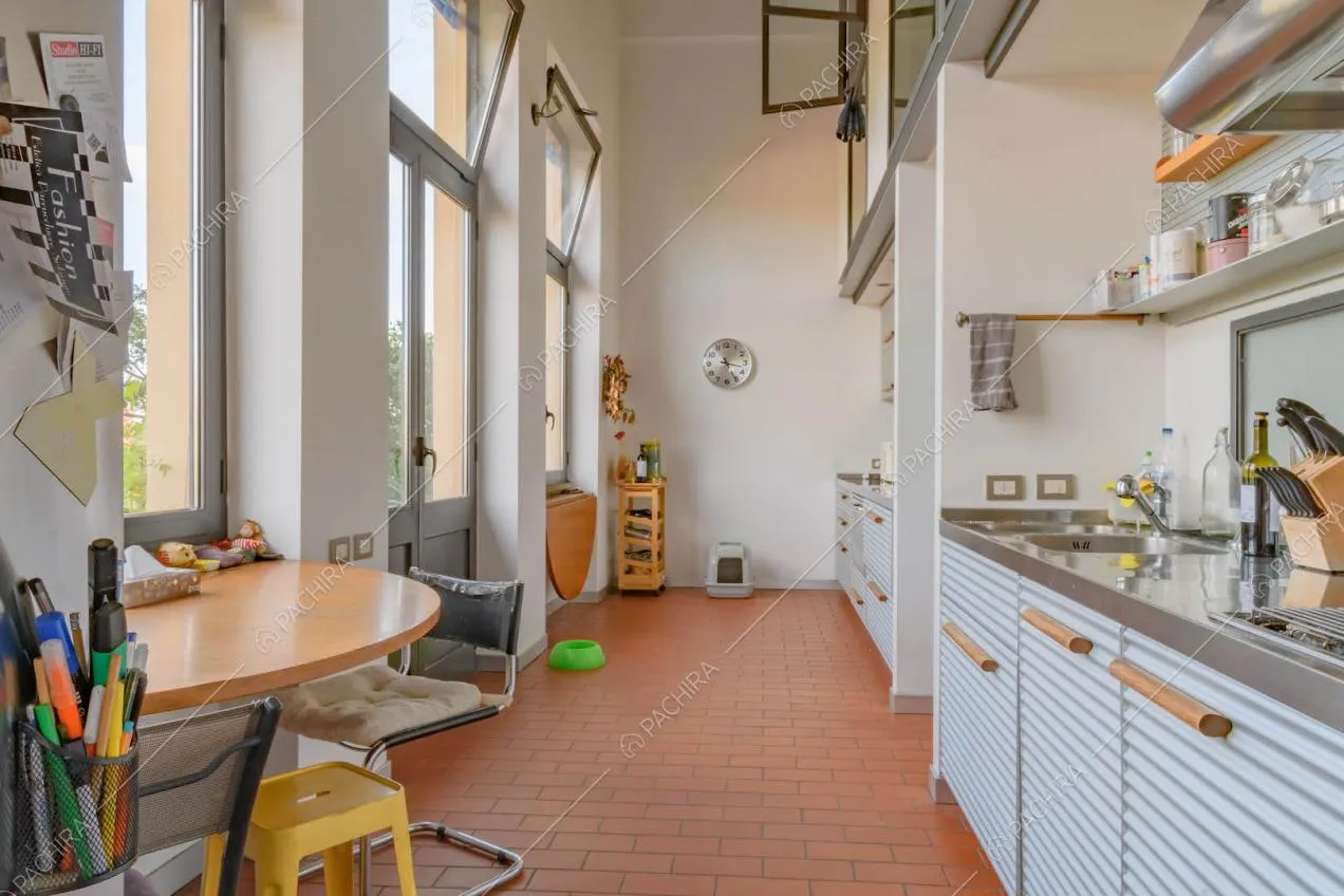 Cucina a parete con pavimento in cotto, pareti bianche e porta-finestra