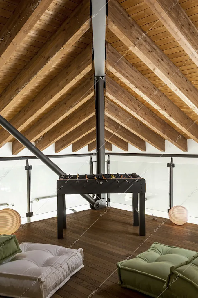 Divanetti e biliardino sul soppalco, soffitto con travi in legno a vista