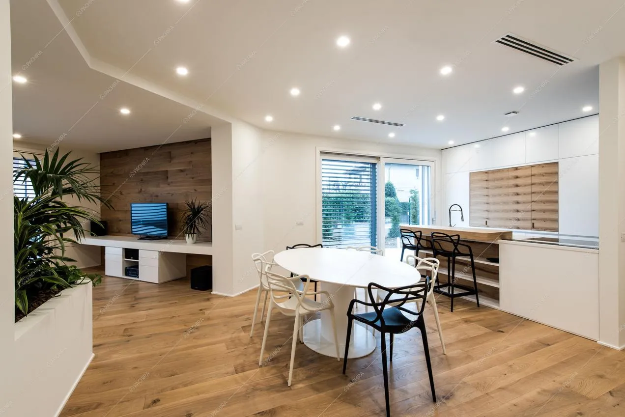 Tavolo da pranzo bianco in metallo e scorcio su zona living e cucina