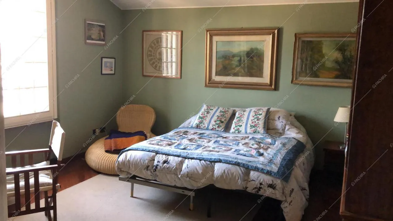 Camera da letto con quadri e poltroncina in vimini