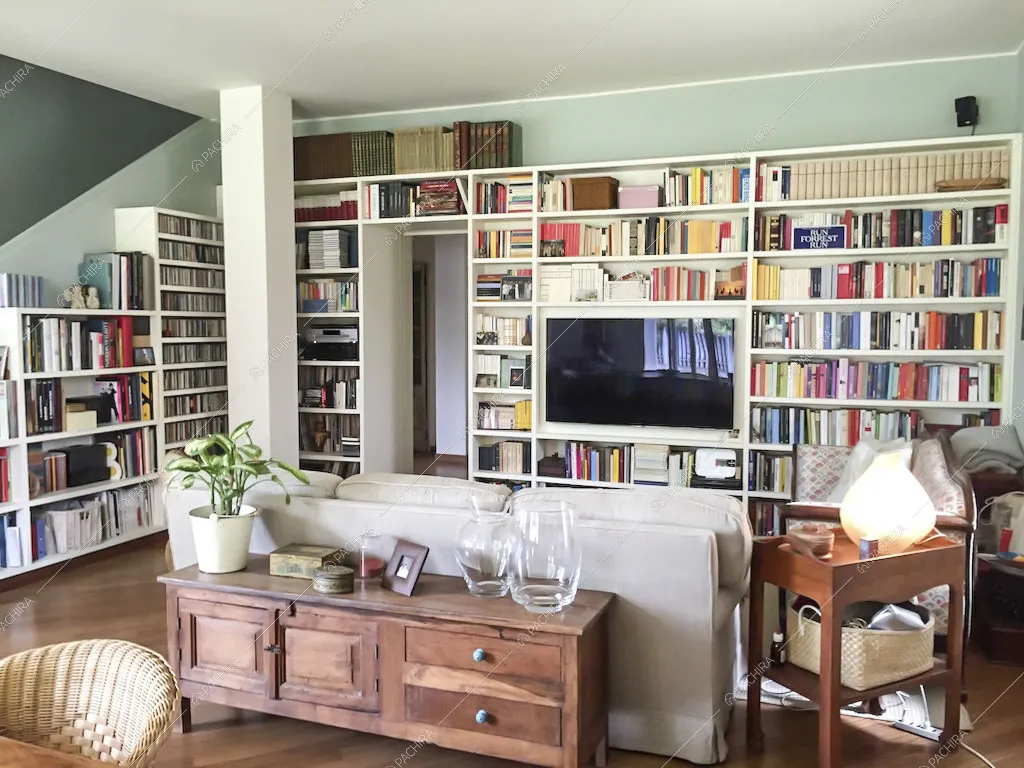 Librerie bianche a parete con tv incassata e zona living