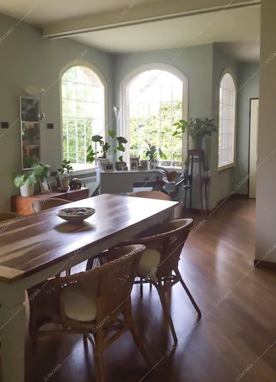 Sala da pranzo con tavolo su pavimento in parquet e vetrate