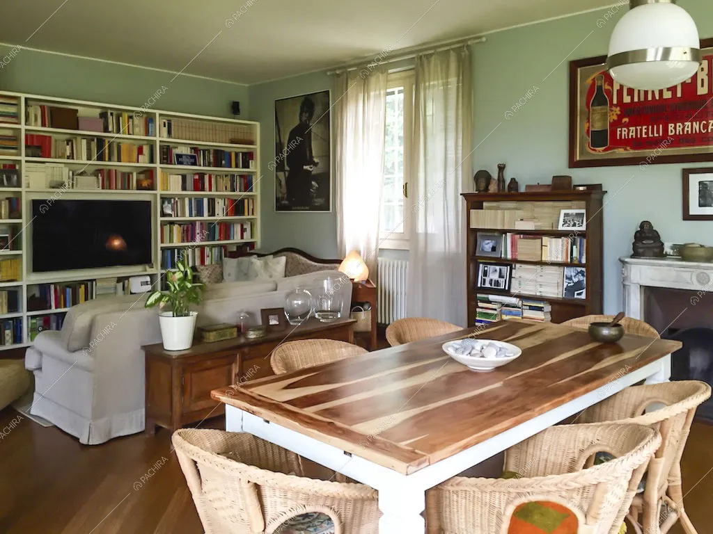 Zona living con tavolo da pranzo in legno e tv incassata nella libreria