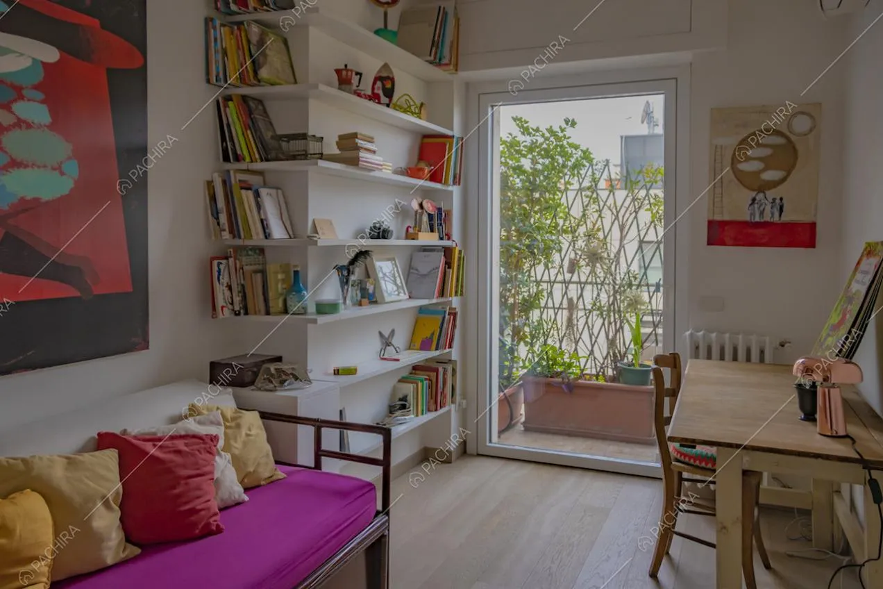 Studio con libreria ad angolo bianca e porta finestra 