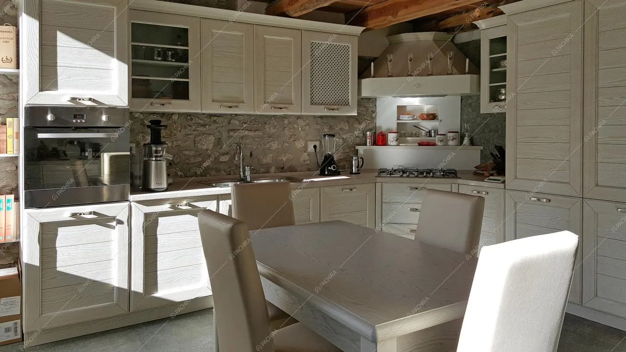 Visuale su cucina in legno con pareti in pietra viva
