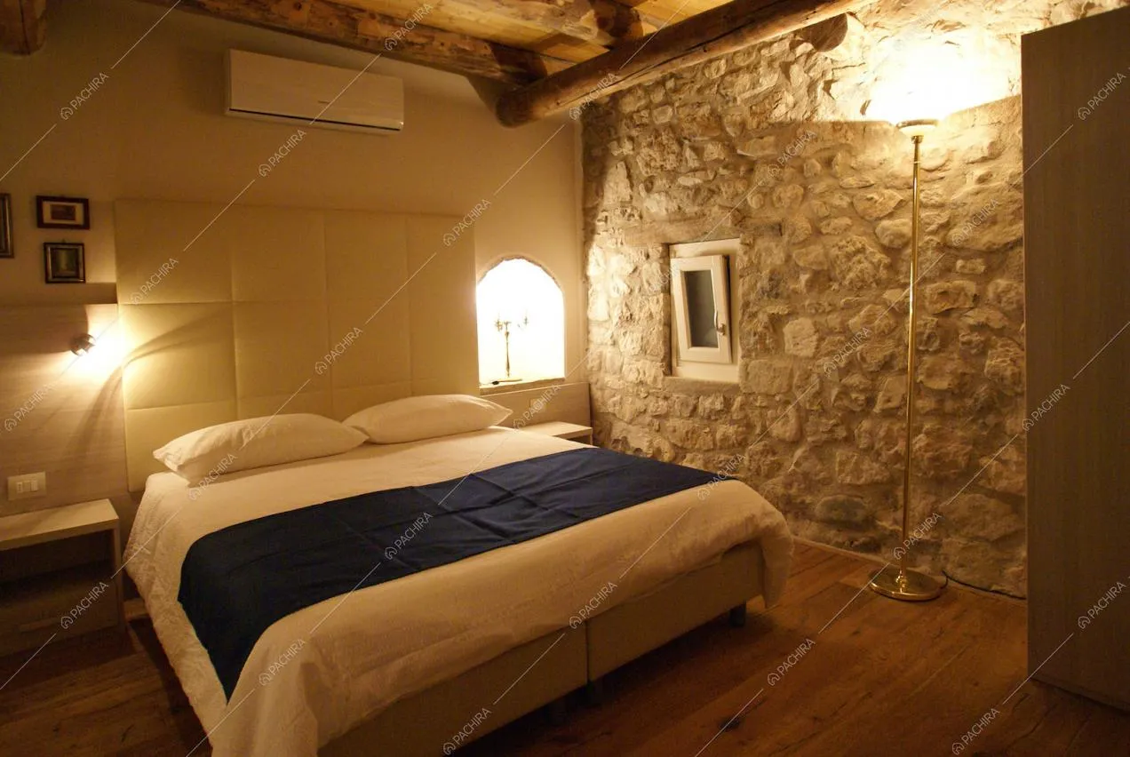 Camera da letto con pavimenti in parquet e pareti in sasso