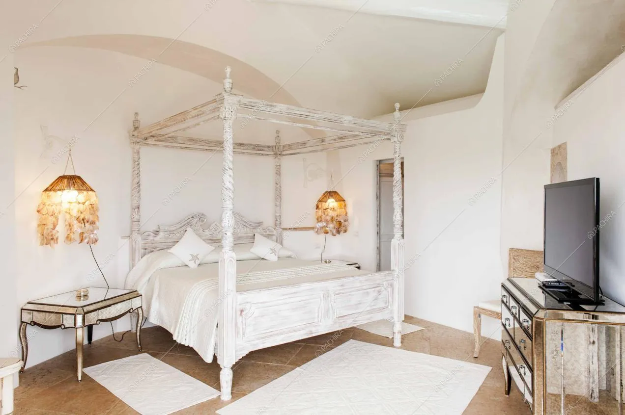 Camera da letto con baldacchino, cassettiera a specchio e televisione