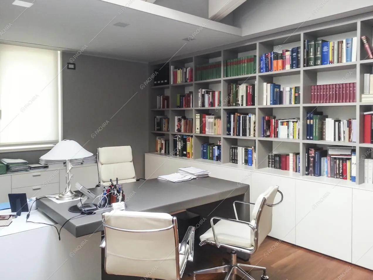 Studio con poltrone bianche e libreria a muro