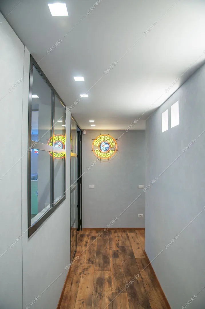 Corridoio con pavimento in parquet a listoni e insegna luminosa
