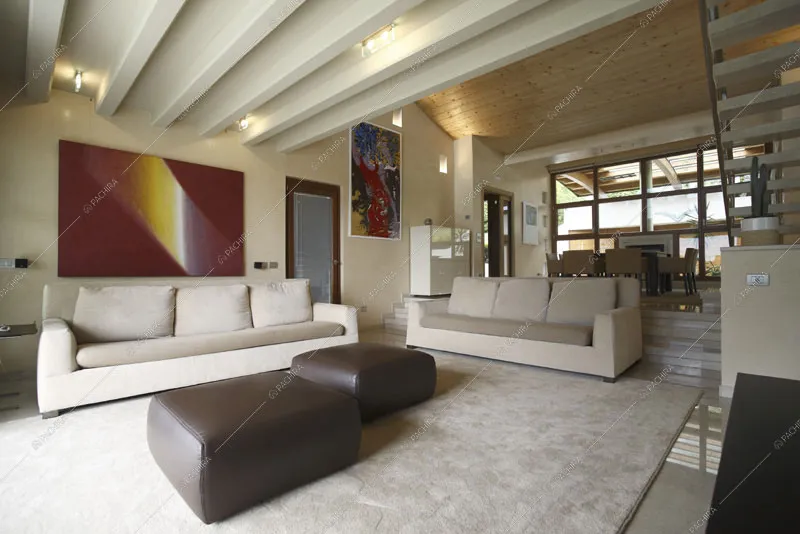 Soffitto con travi a vista e scorcio sul tavolo da pranzo dalla zona living