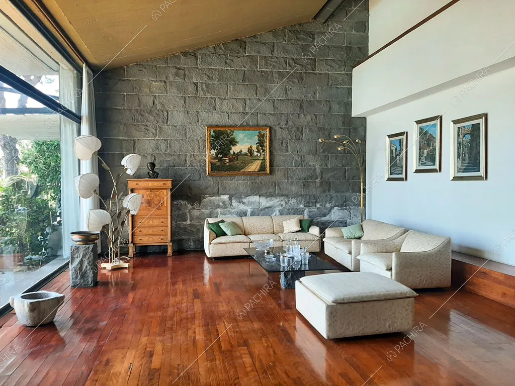 Luminosa zona living con pavimento in parquet, divani bianchi, poltrona e pouf
