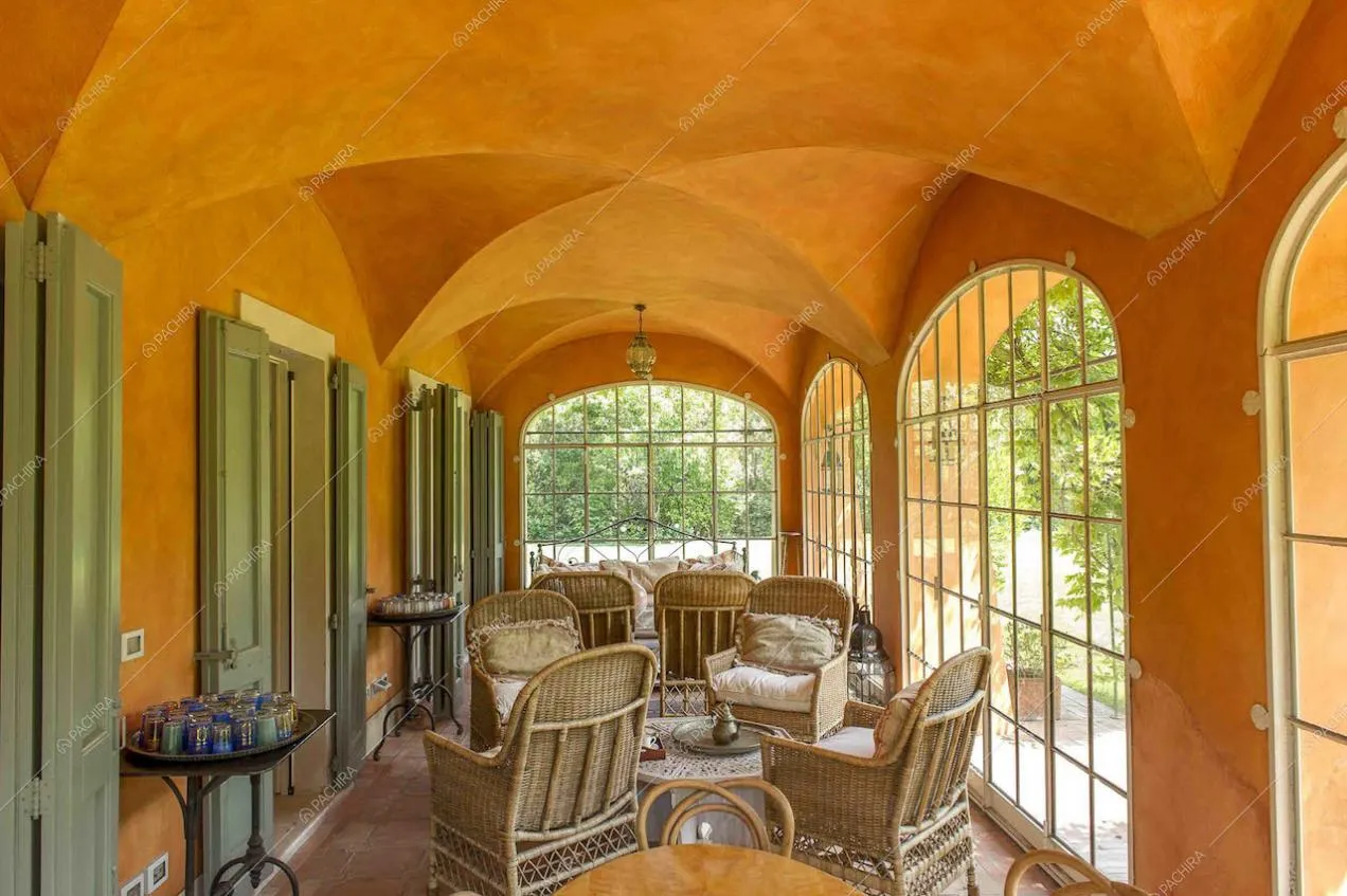 Soffitto arancione a volte con poltroncine in vimini