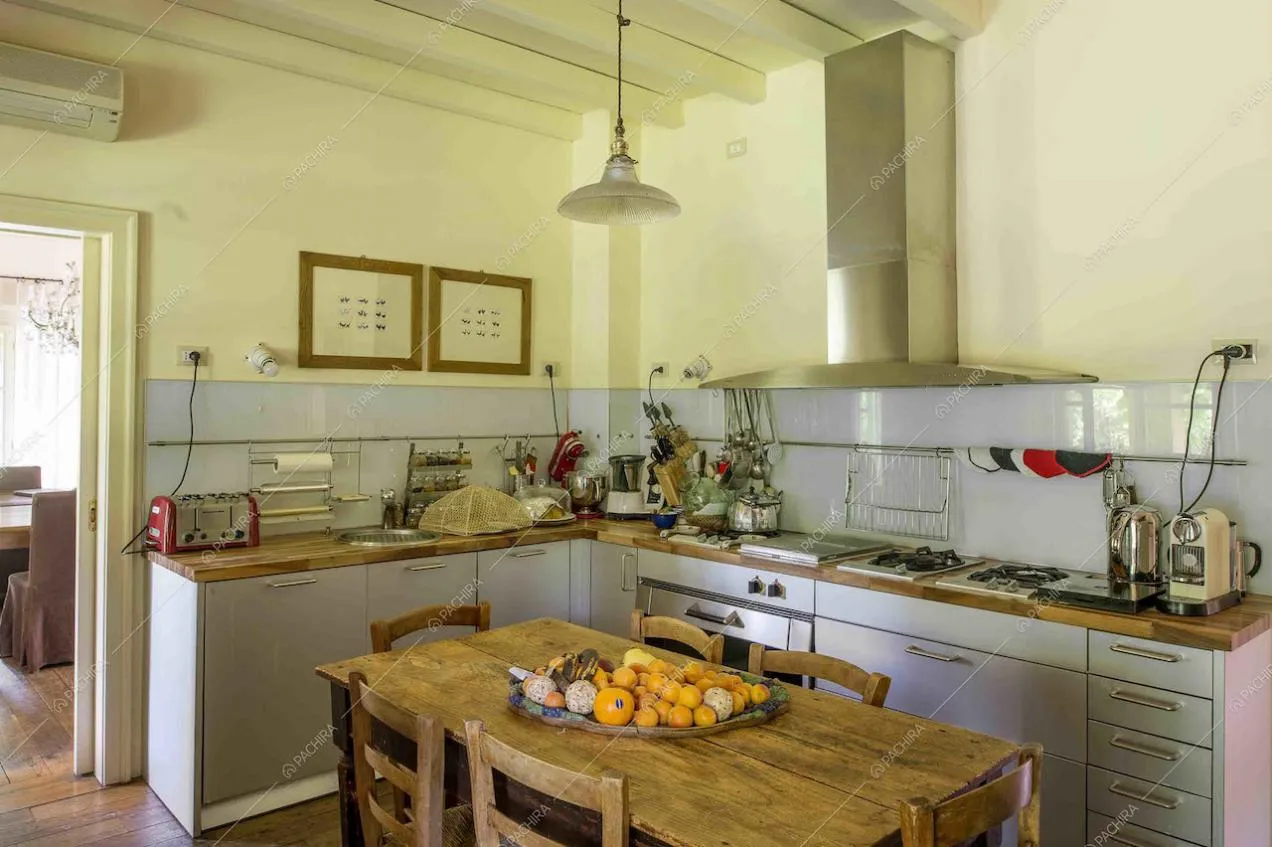 Cucina a parete con fornelli a gas, piano di lavoro in legno e tavolo da pranzo