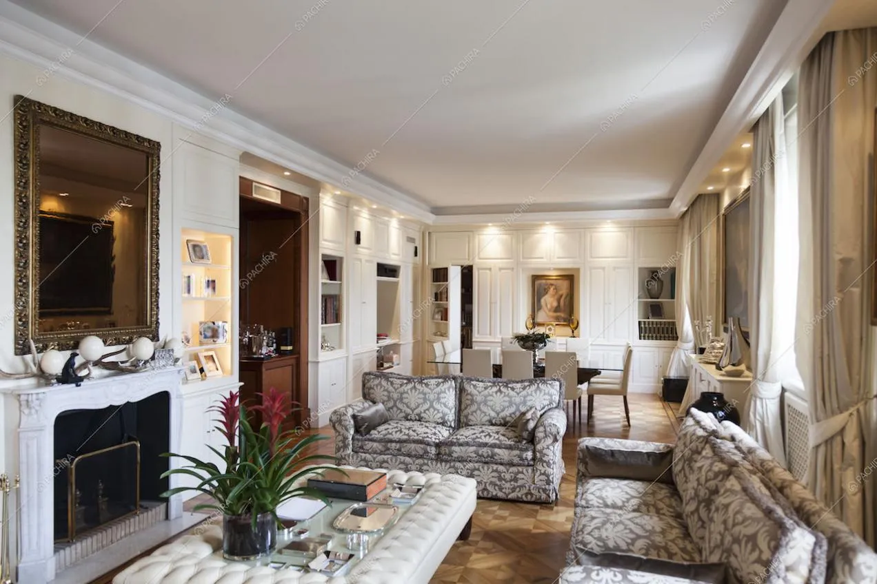 Zona living con camino, pareti bianche con boiserie e parquet