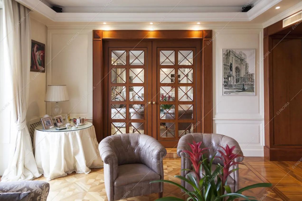 Soggiorno con poltrone e porta in legno a specchio