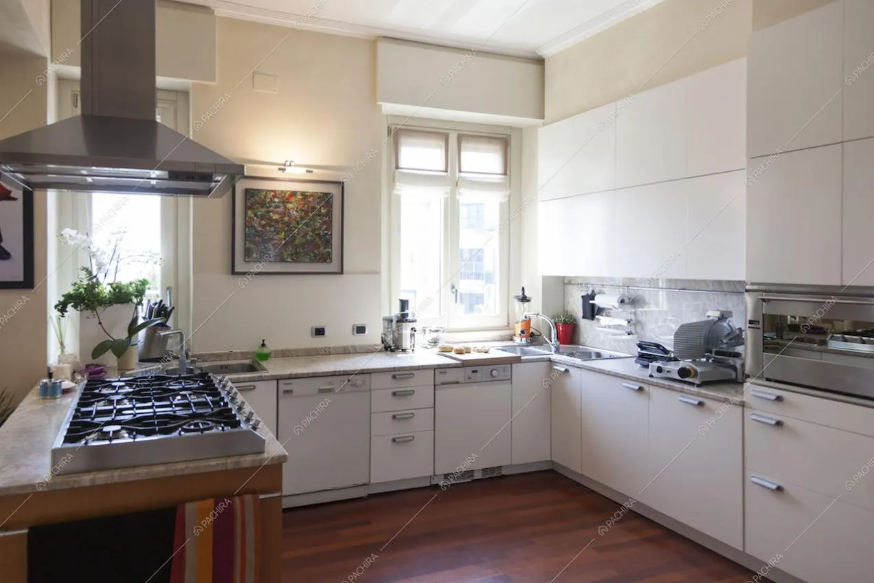Cucina con penisola bianca, fornelli a gas, parquet a listoni