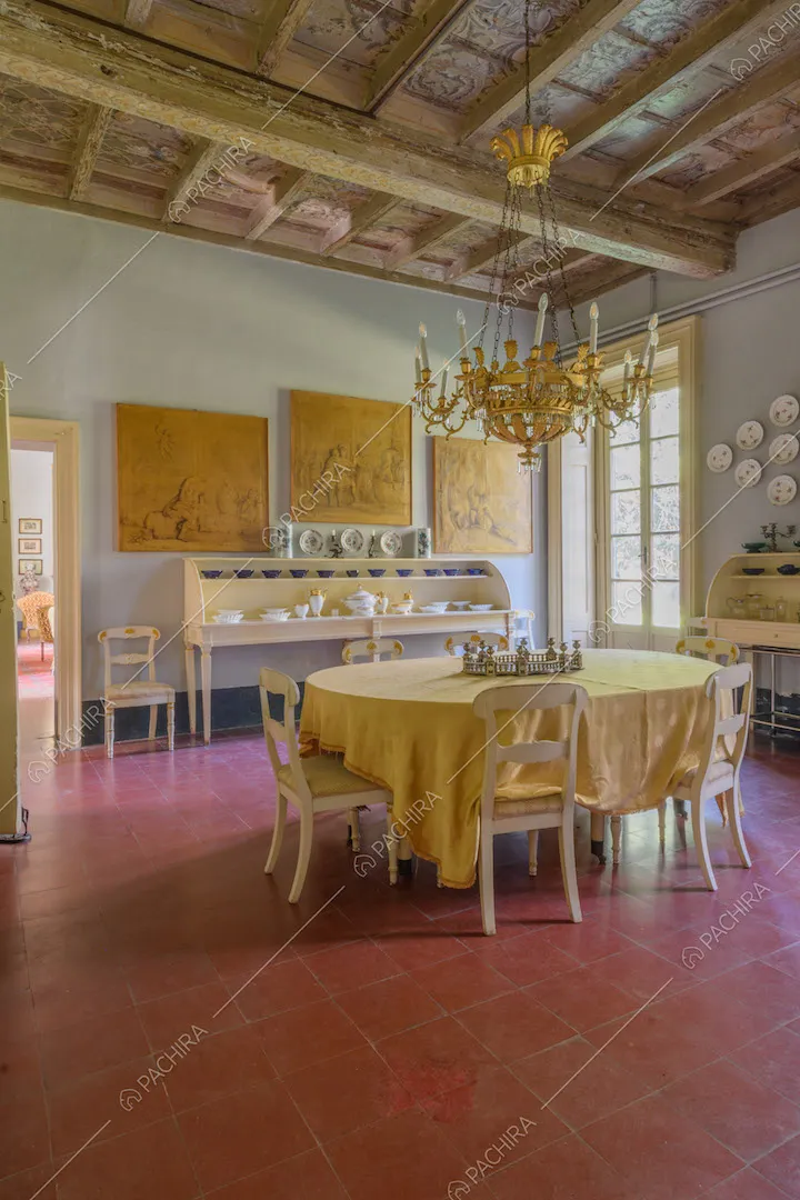 Grande sala da pranzo con pavimento in piastrelle rosse, soffitto a cassettoni e porta-finestra