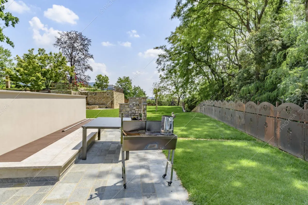 Nel giardino privato, cancello in metallo, barbecue e pavimentazione in lastre di pietra