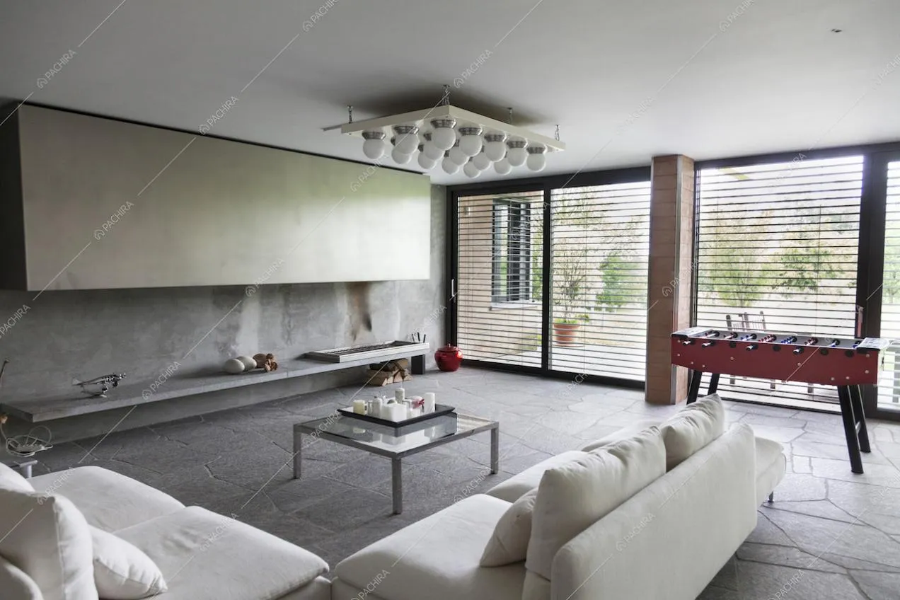 Vetrate, lampadario di design e calcetto nel soggiorno