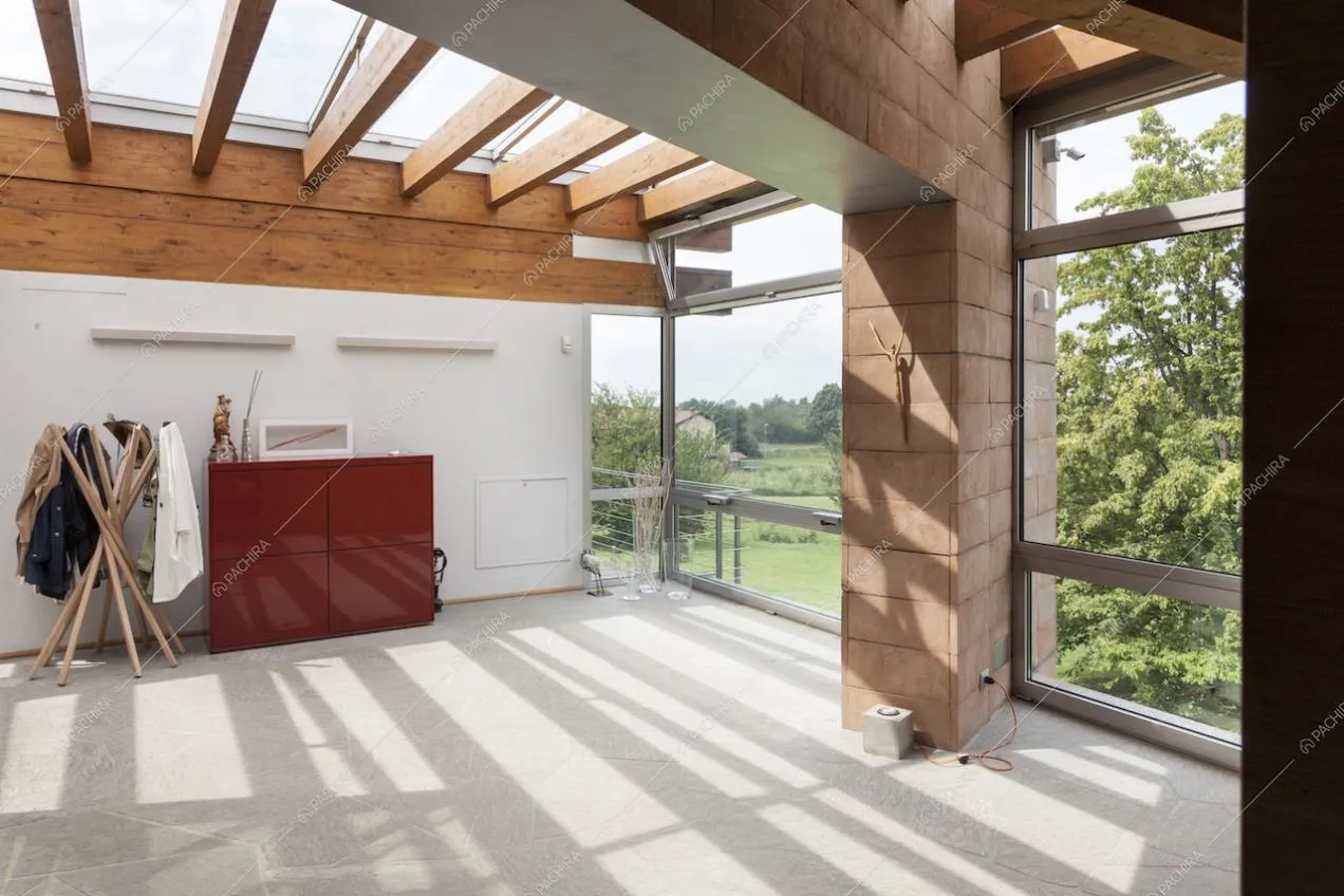 Spazio al livello superiore con travi a vista, soffitto in vetro e vetrate