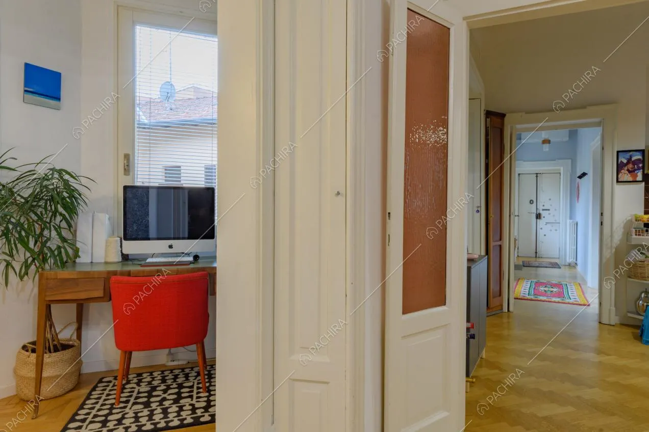 Studio con scrivania in legno, sedia rossa e vista sulla porta d'ingresso